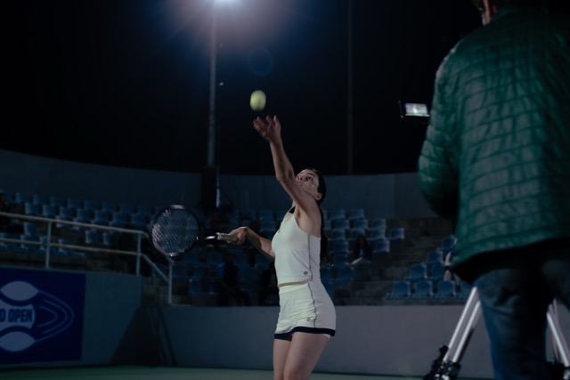 Isa serving under stadium lights at night